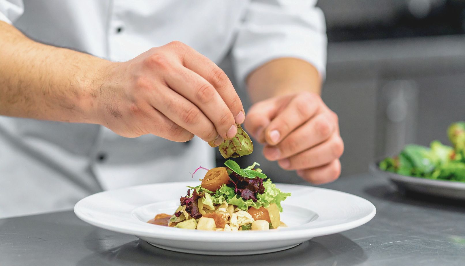 Chef finishing a plated dish by hand